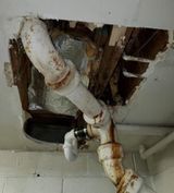 a pipe is coming out of the ceiling in a bathroom .