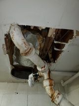 a pipe is hanging from the ceiling in a bathroom .