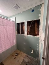 a bathroom under construction with a pink shower curtain .