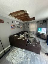 a living room with a hole in the ceiling and a couch .