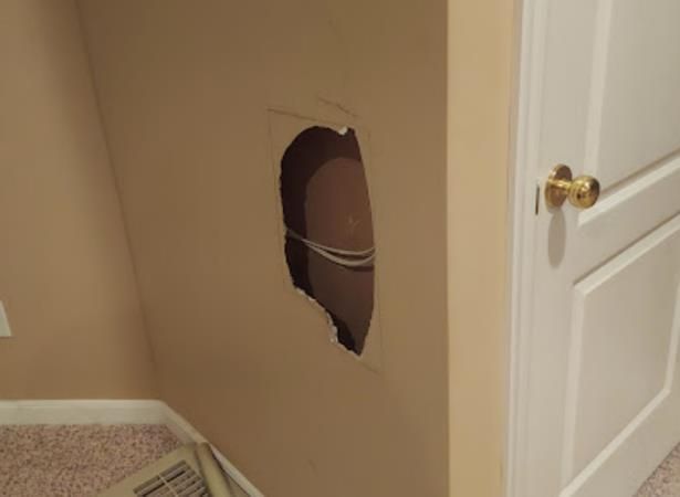 a hole in a wall next to a door in a room .