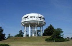 A water tower with horses painted on it is on top of a hill.