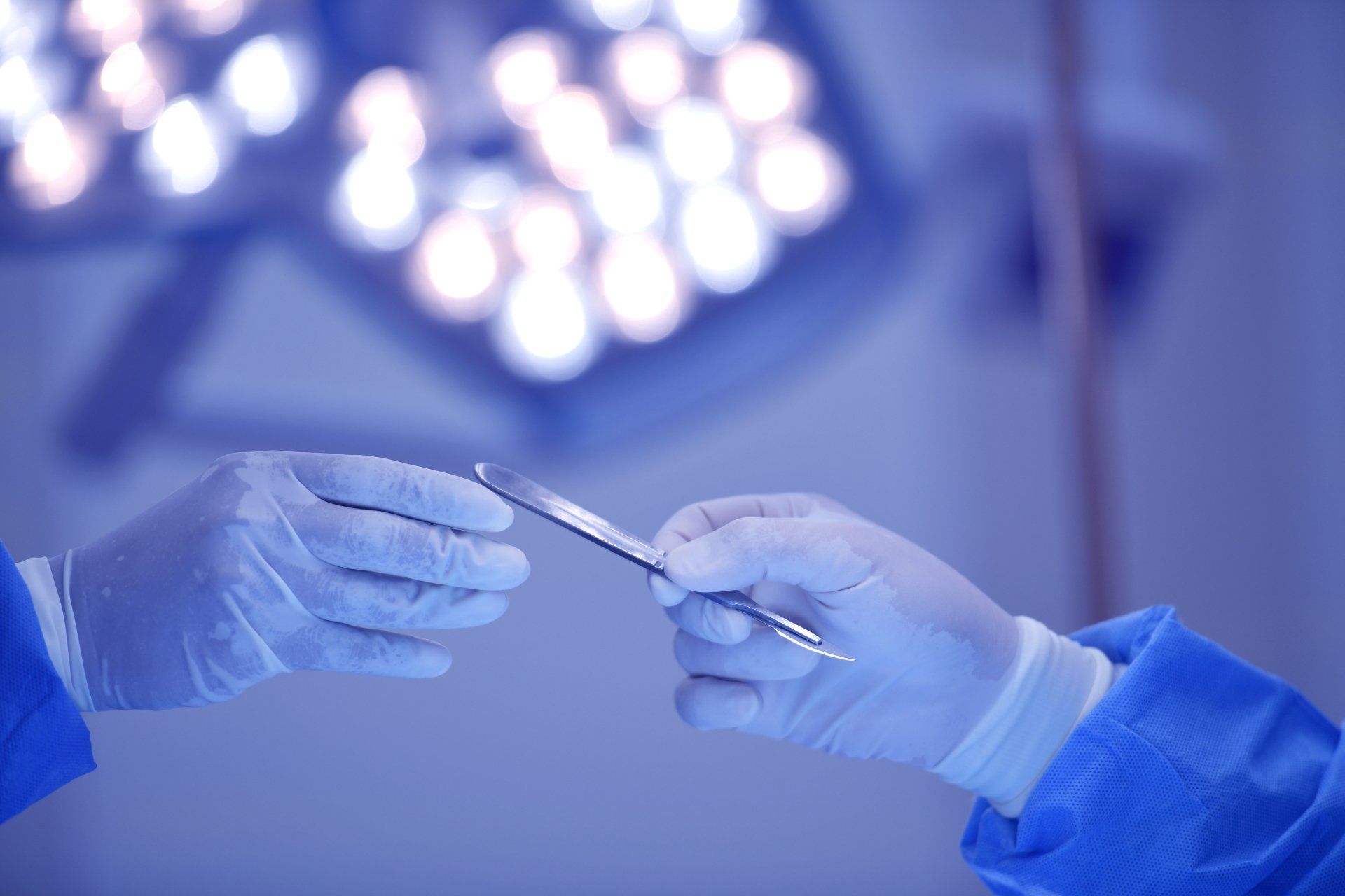 A surgeon is holding a pair of scissors in an operating room.