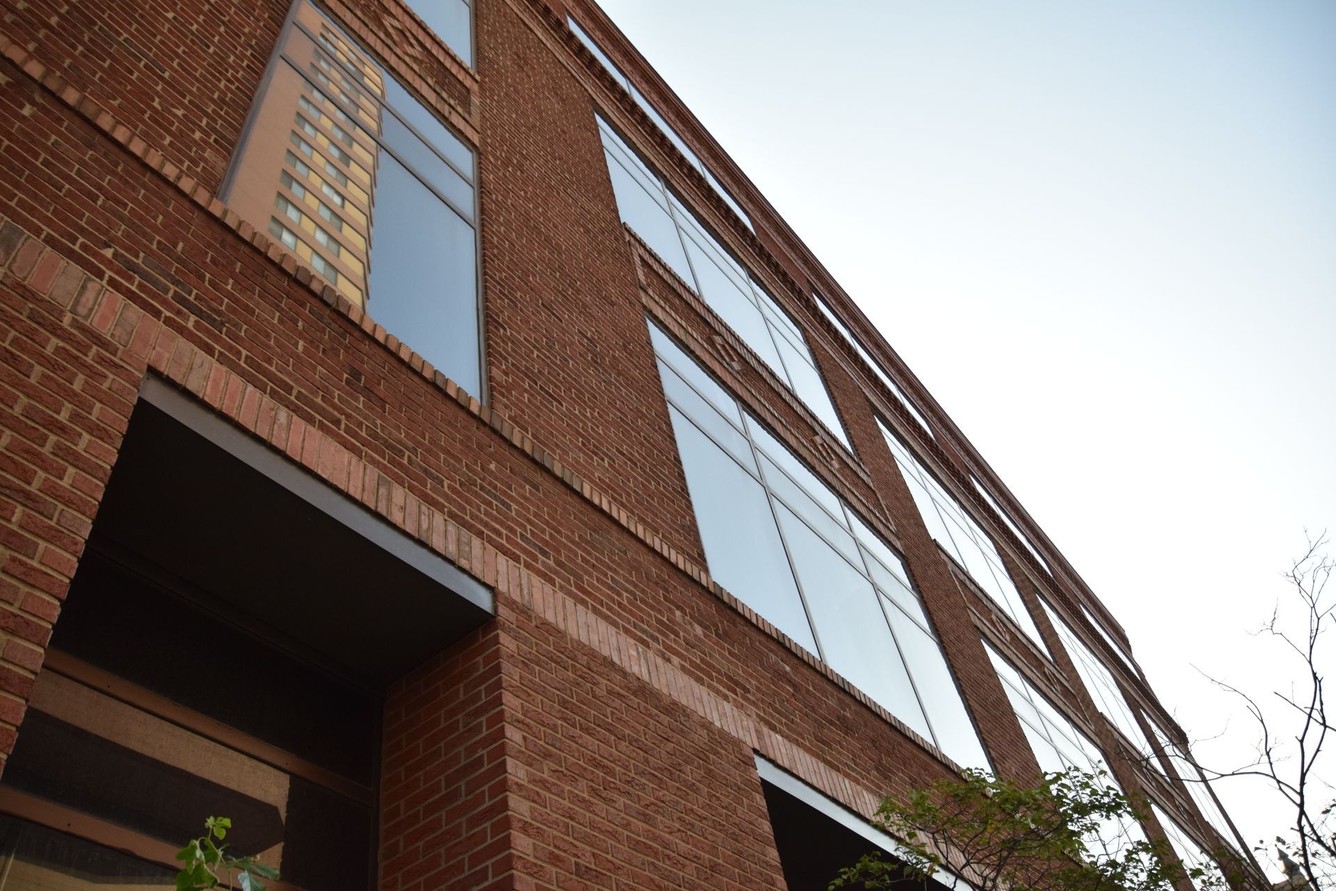 Brick building with large windows, angled upward against a clear sky.