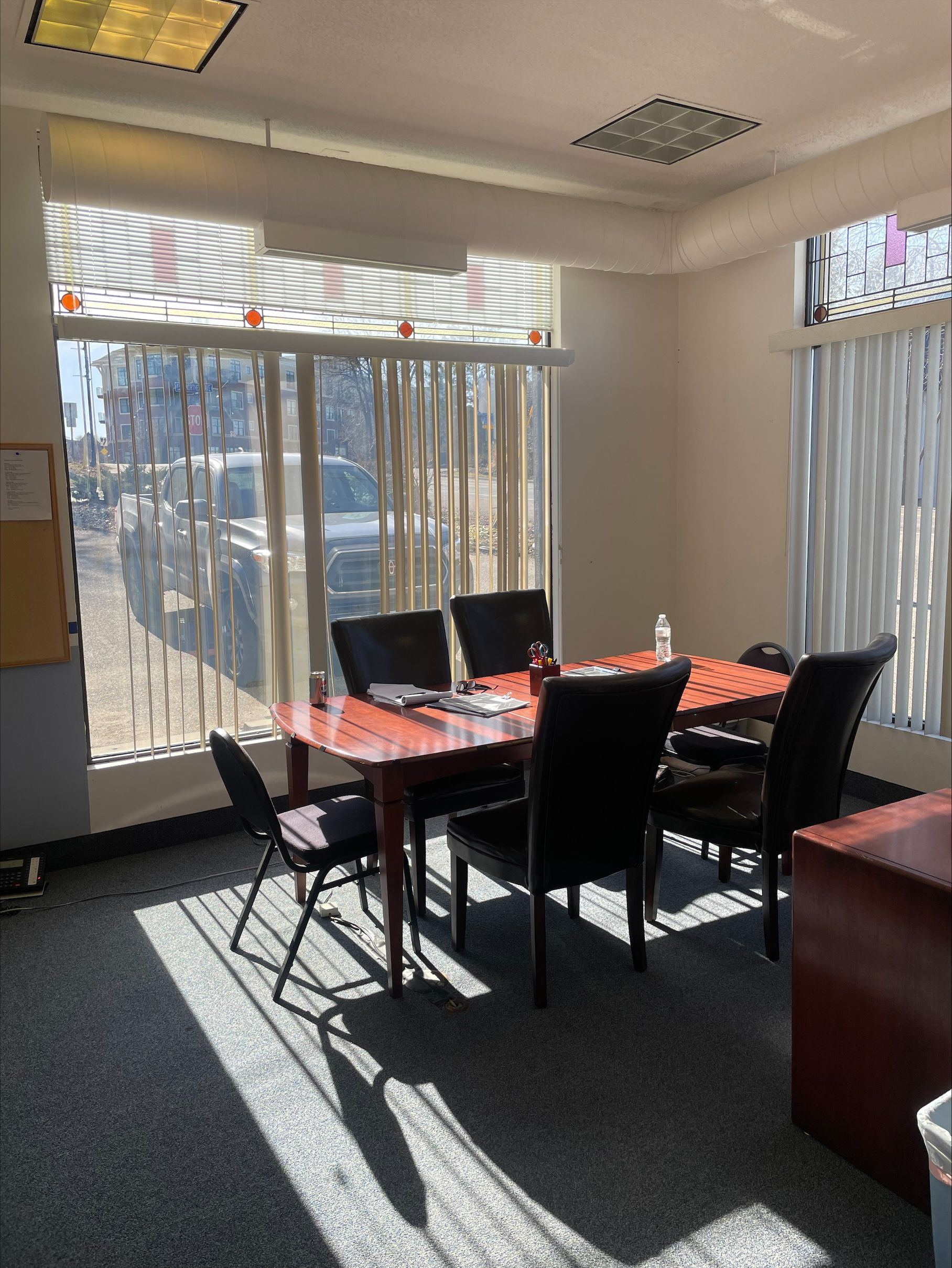 Meeting room with table, chairs, window blinds, and natural light.