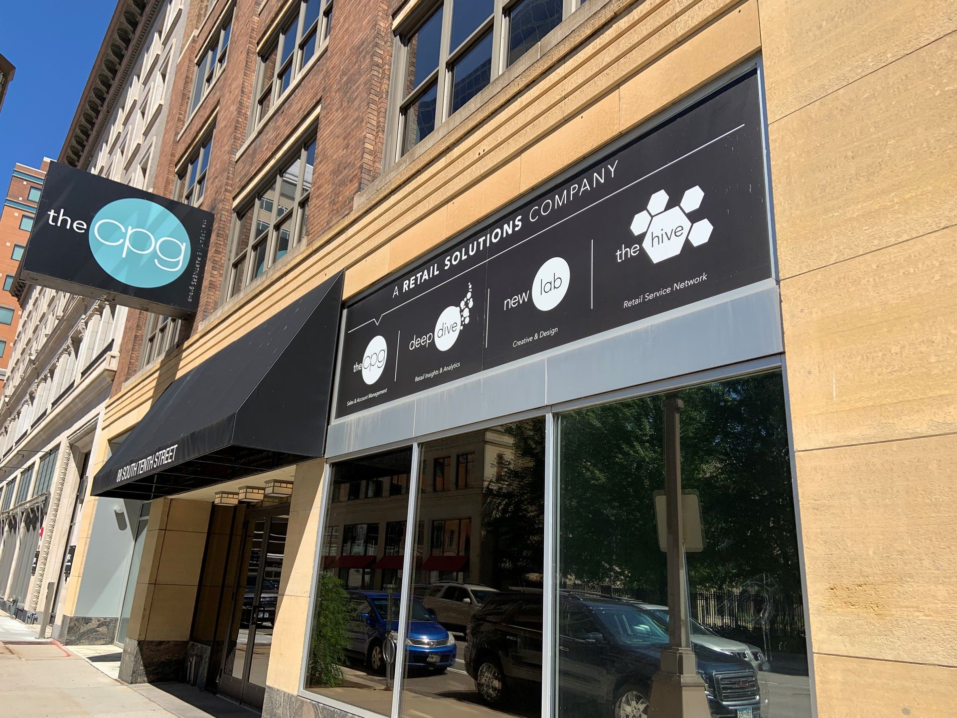 Exterior of building with a black awning and signage on a city street.