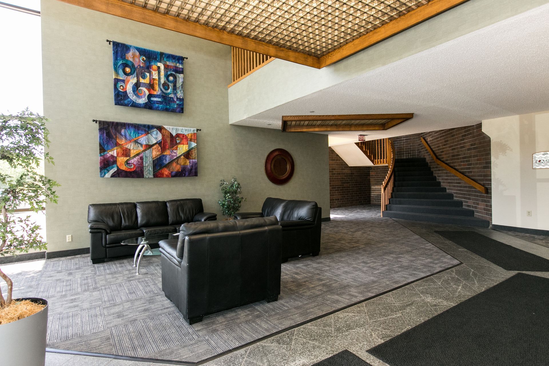 Lobby with black leather seating, colorful wall art, and stairs.