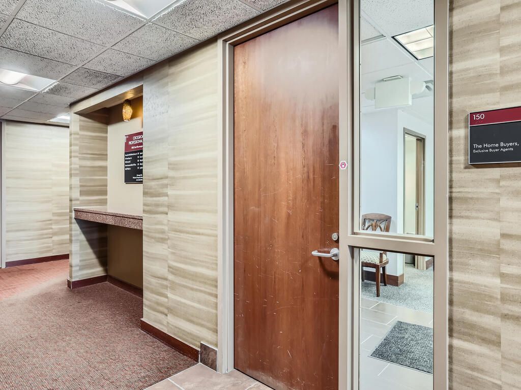 Hallway with a wooden door and glass panel. Beige and brown walls, red carpet.