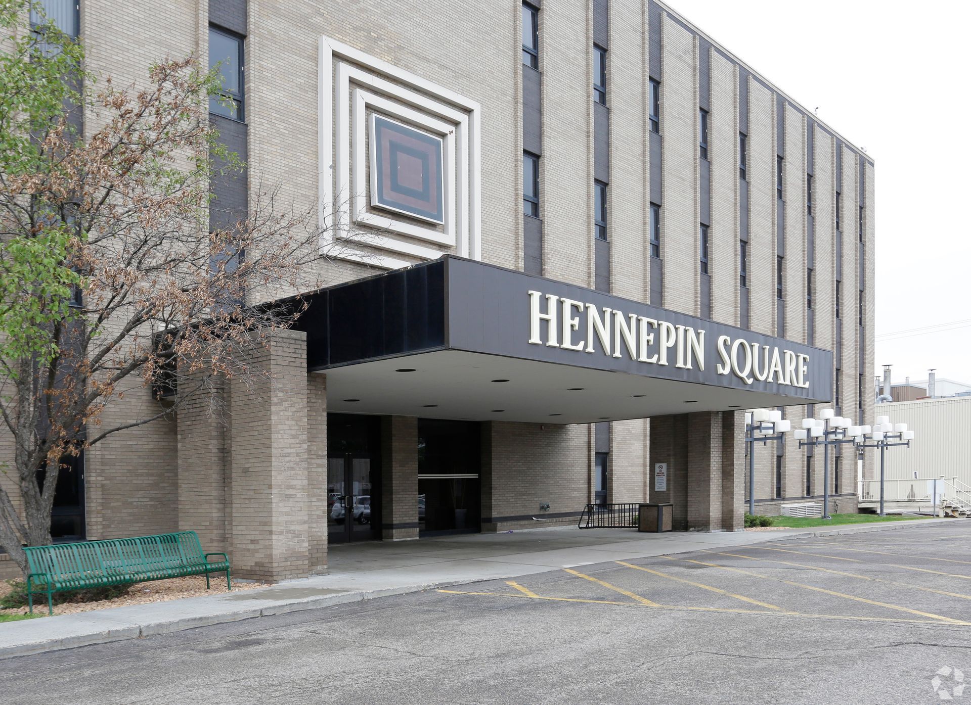 Hennepin Square building entrance with a black awning and gray brick exterior.