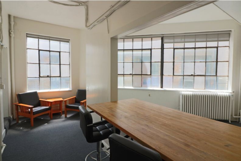 Office meeting room with large windows, wooden table, chairs.