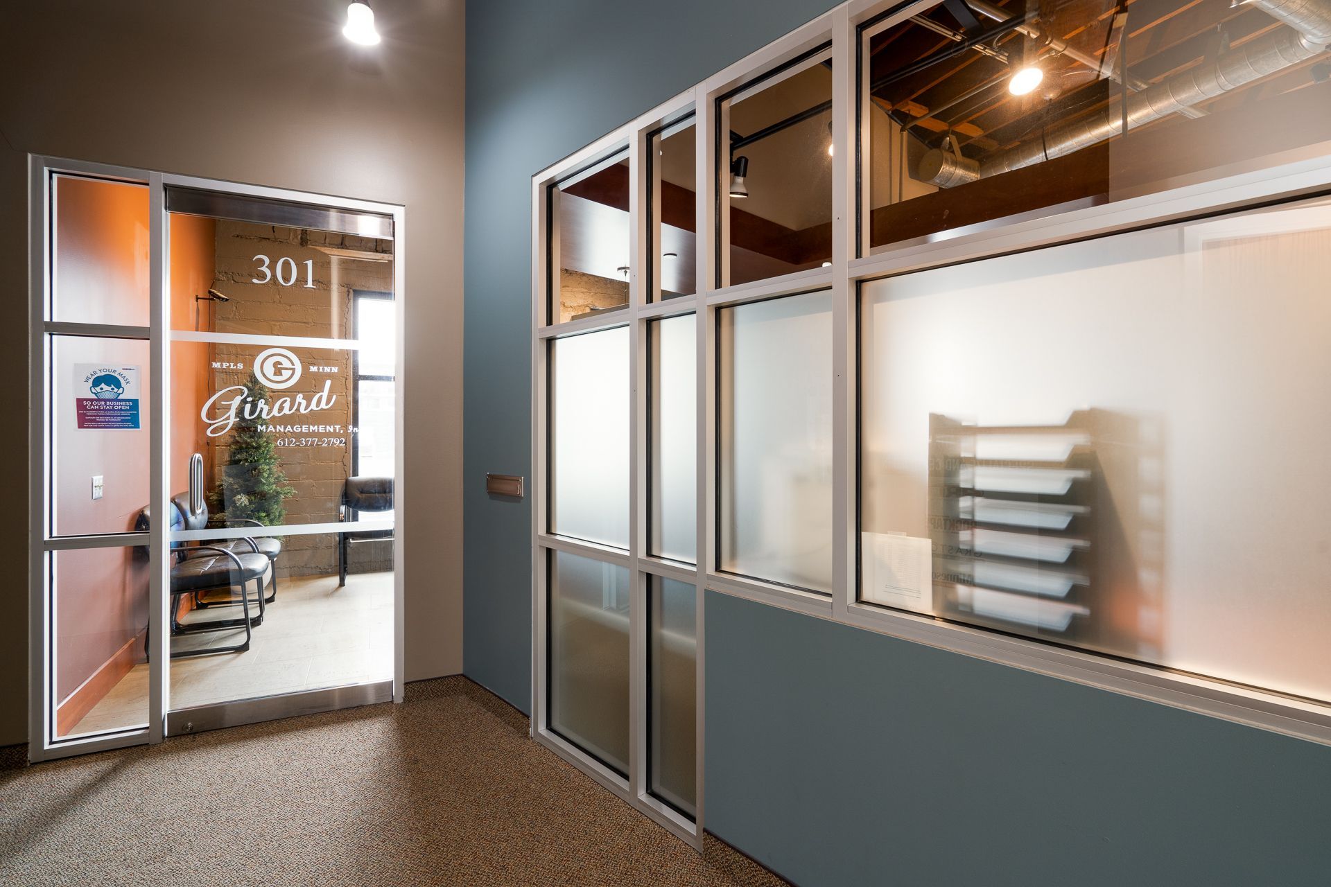Hallway with office door and frosted glass windows. Teal walls, beige carpet.