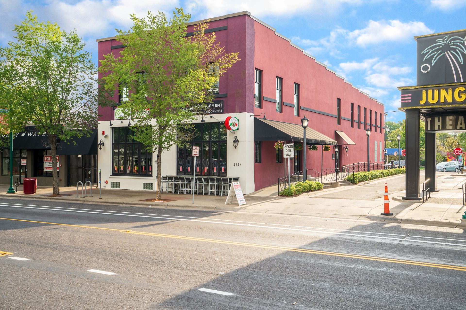 Street view of a two-story brick building, a restaurant with outdoor seating. Red brick exterior. Next to a theater.