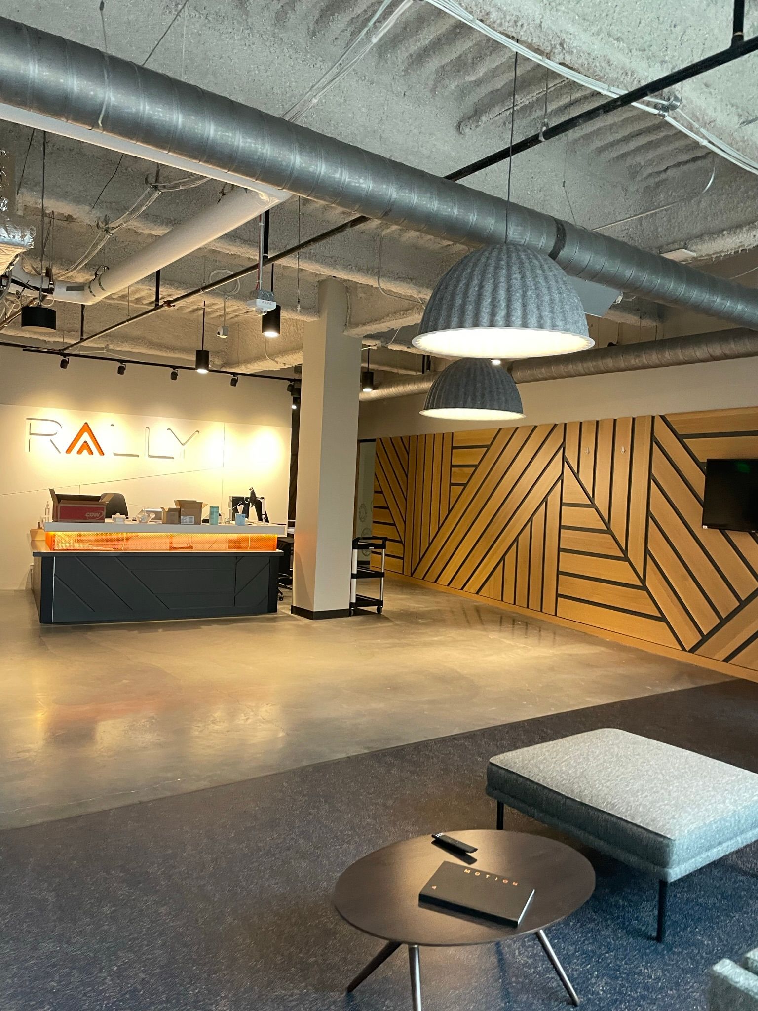 Reception area of office: modern design with wooden accent wall, hanging lights, and seating.