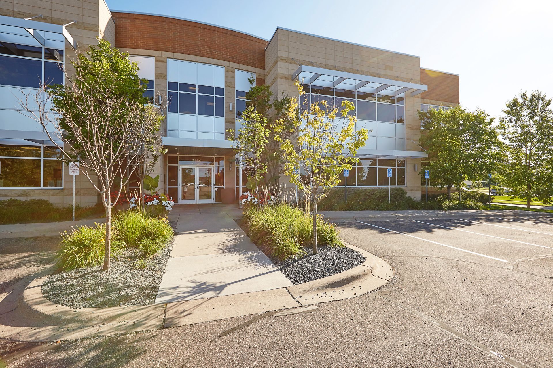 Modern office building with glass windows, brick facade, and landscaping.
