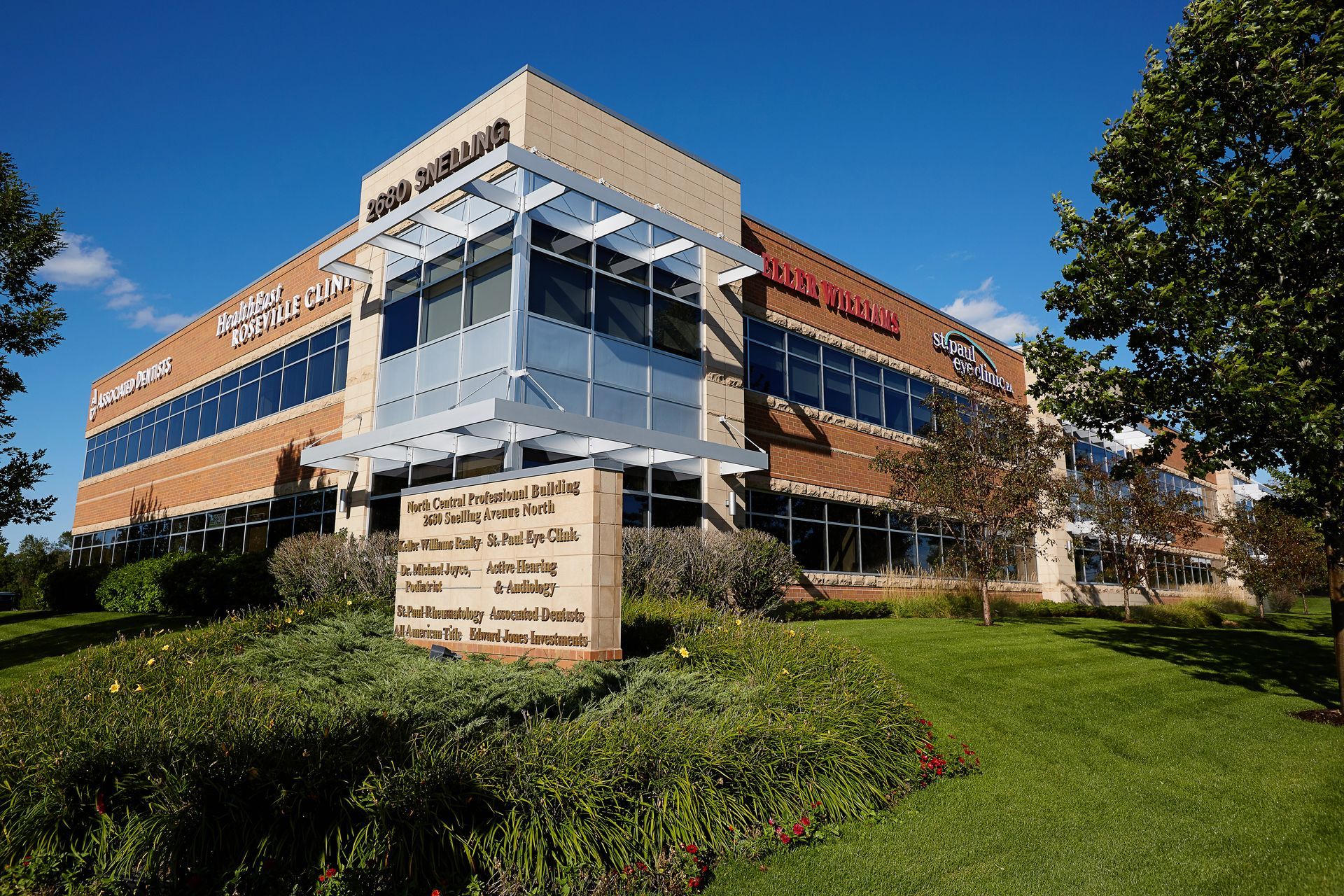 Multi-story office building with glass and brick exterior, under a clear blue sky.