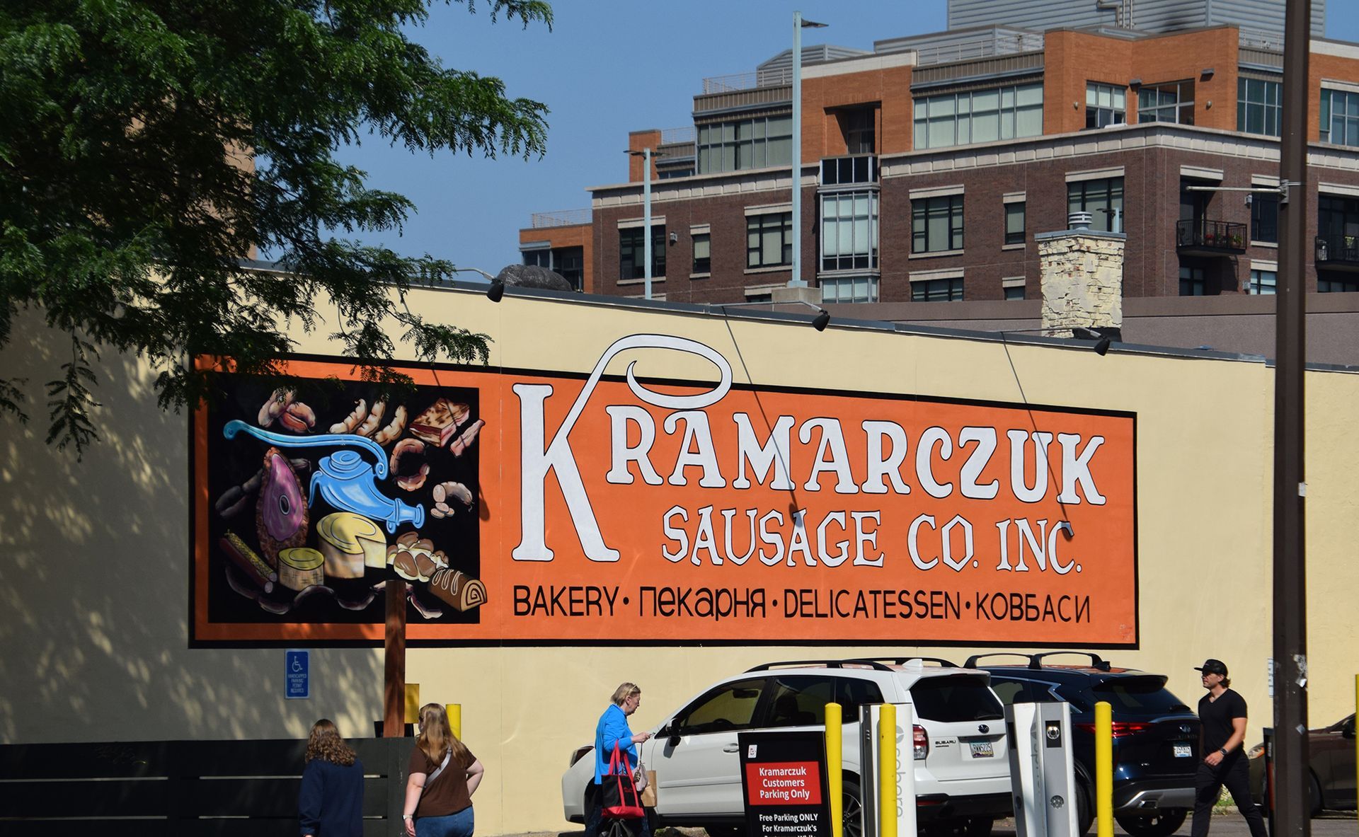 Kramarczuk Sausage Co. sign in front of a building, bakery, deli, with cars parked below.