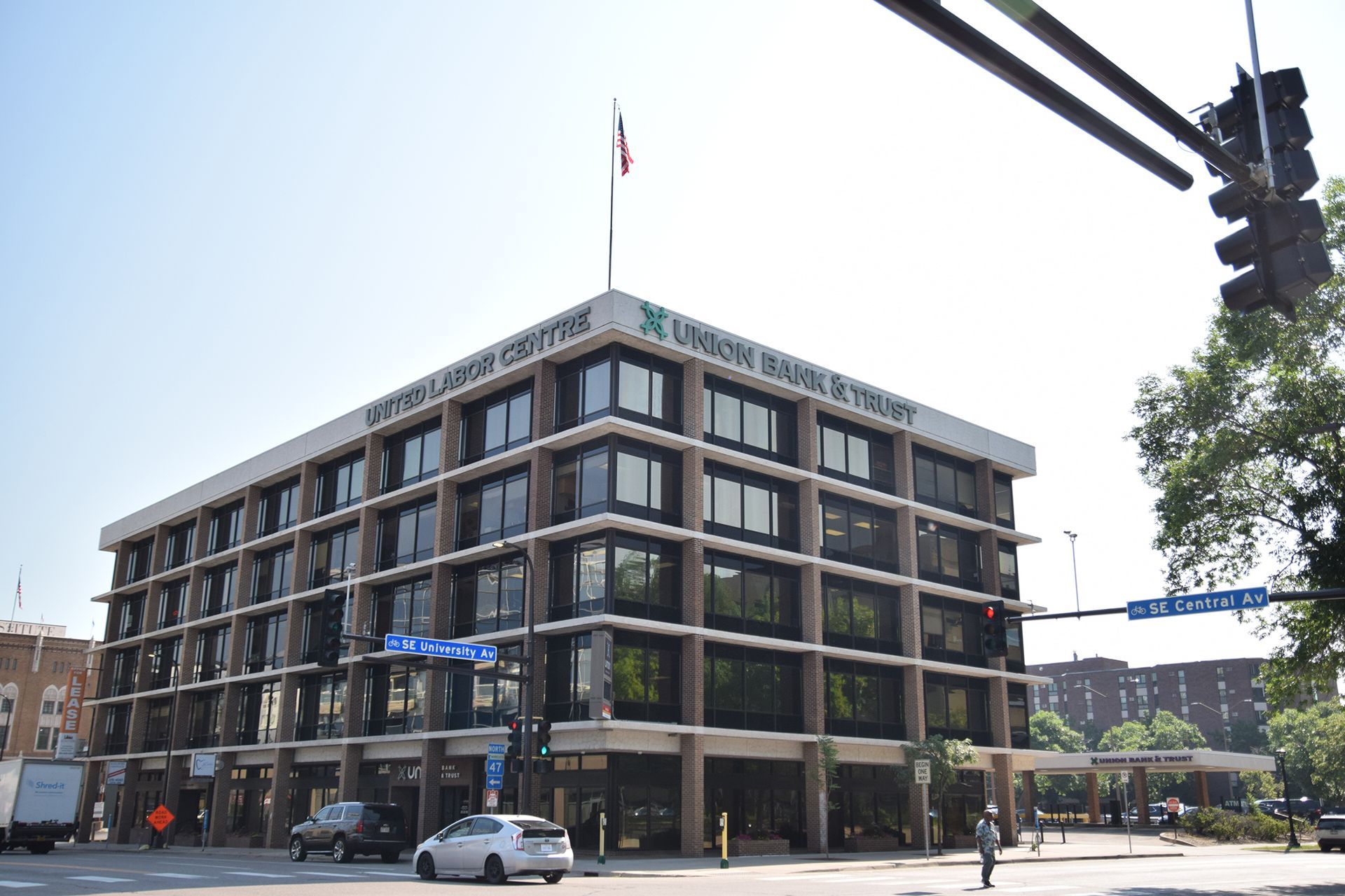 Office building with United Labor Centre sign on corner. Cars and pedestrians on street.