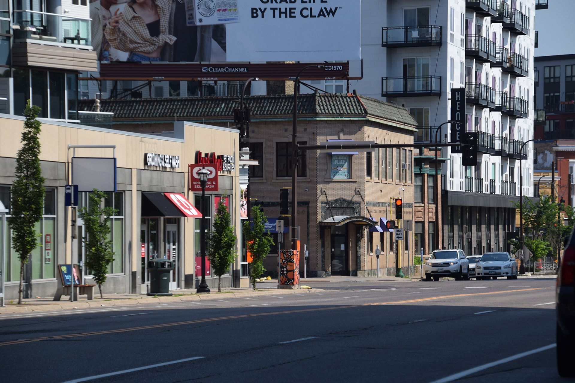 Street view of buildings, businesses, cars, and traffic lights on a sunny day.