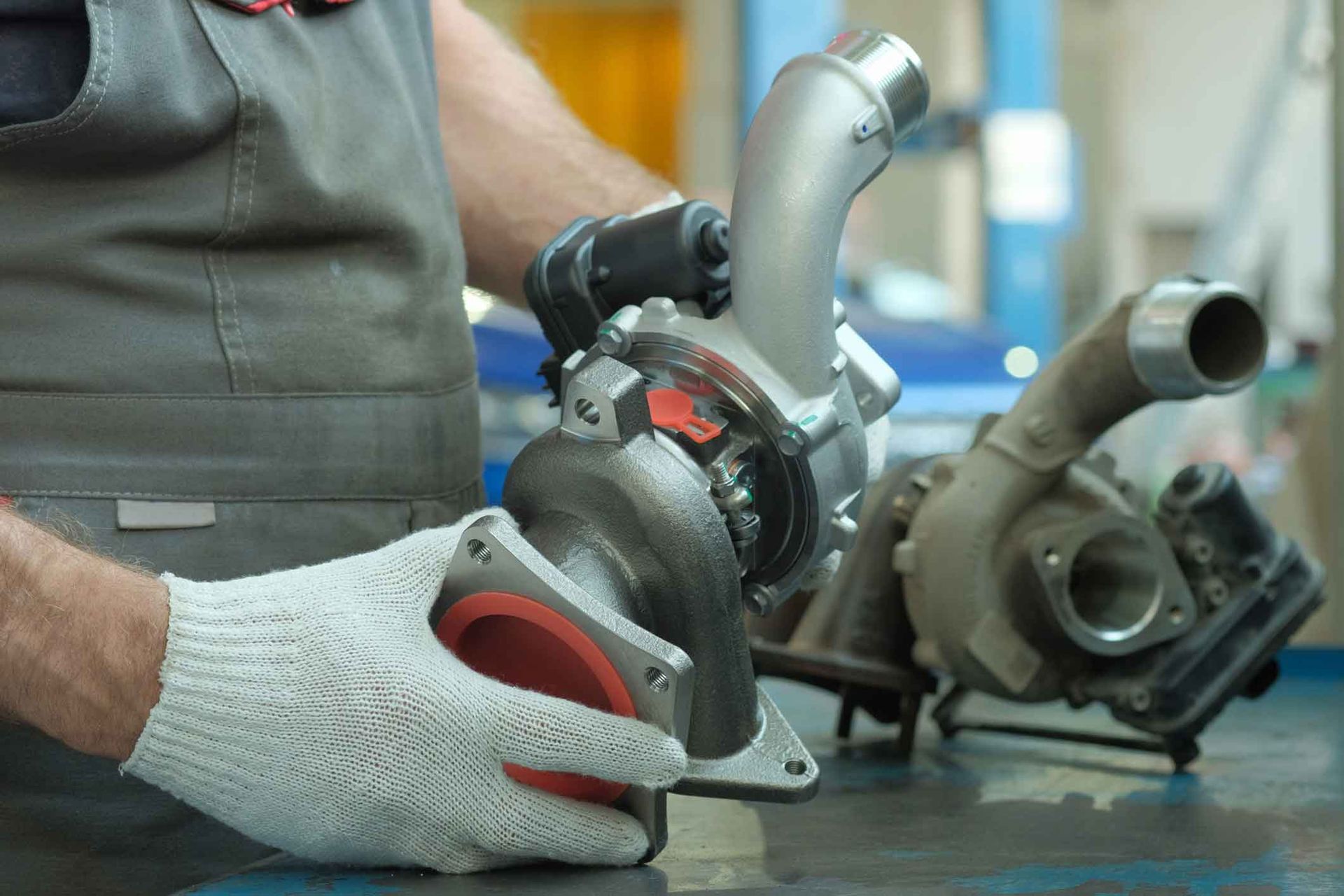 A man is working on a turbocharger in a garage.