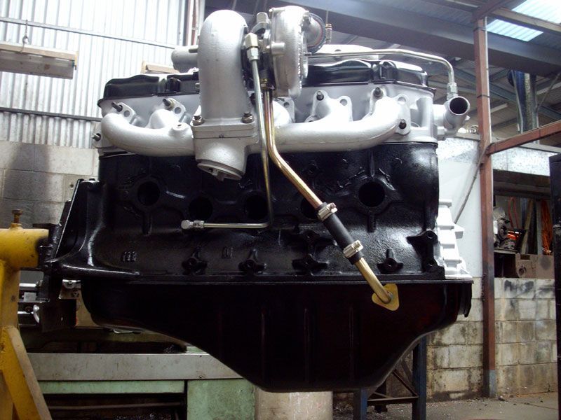 A black engine is sitting on a stand in a garage