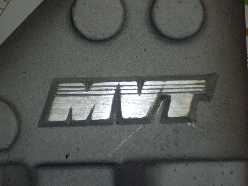 A close up of a mvt logo on a gray surface