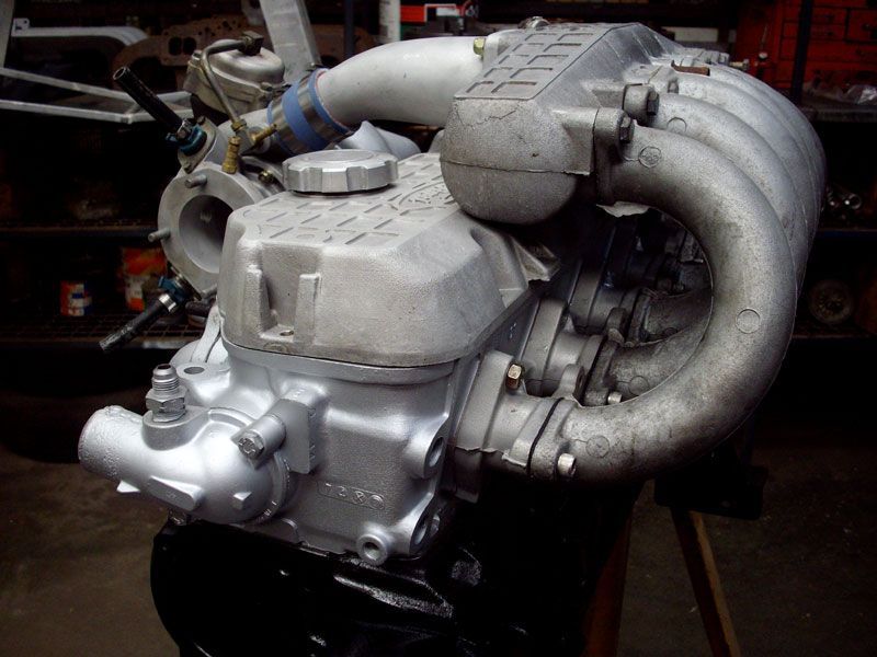 A motorcycle engine is sitting on a wooden table in a garage.