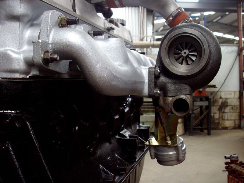 A turbocharger is attached to the side of a car engine