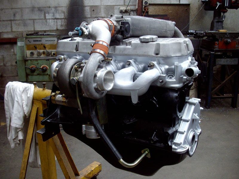 A car engine is sitting on a wooden stand in a garage