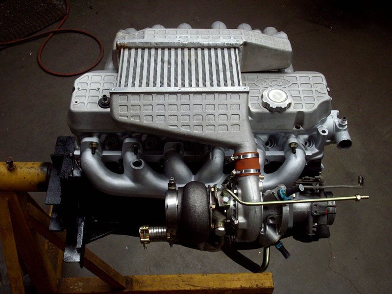 A silver engine is sitting on a wooden stand