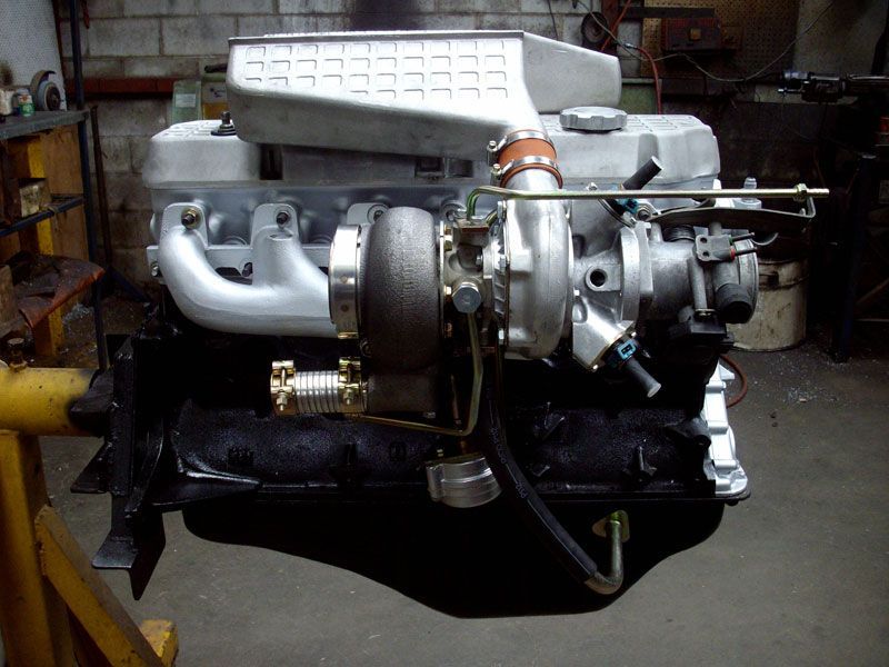 A turbocharged engine is sitting on a yellow stand