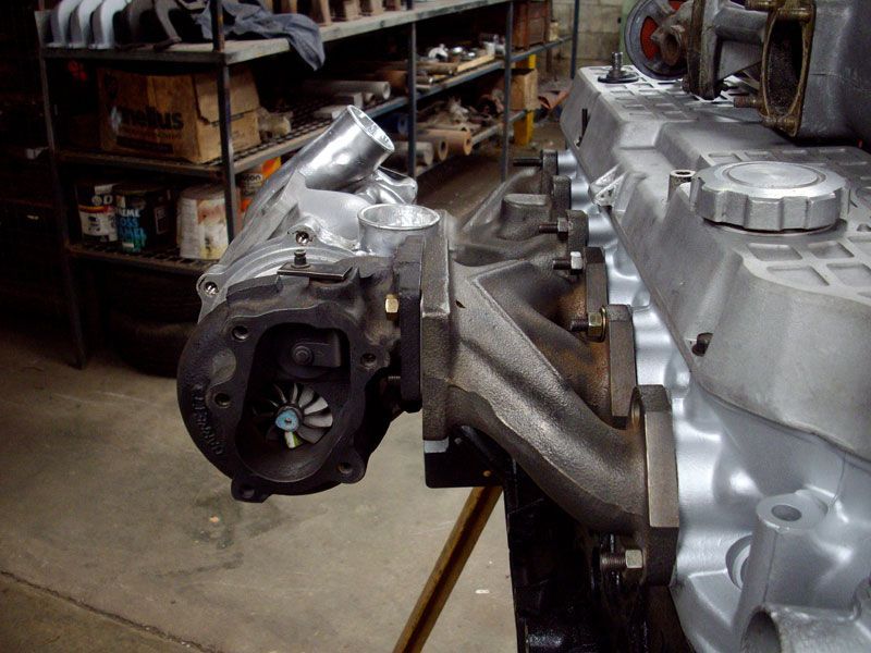 A turbocharger is attached to the side of a car engine