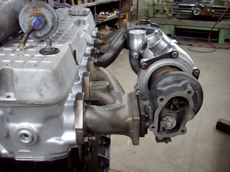 A turbocharger is attached to the side of a car engine