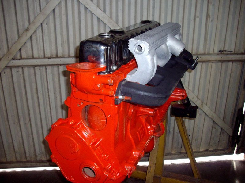 An orange engine is sitting on a yellow stand