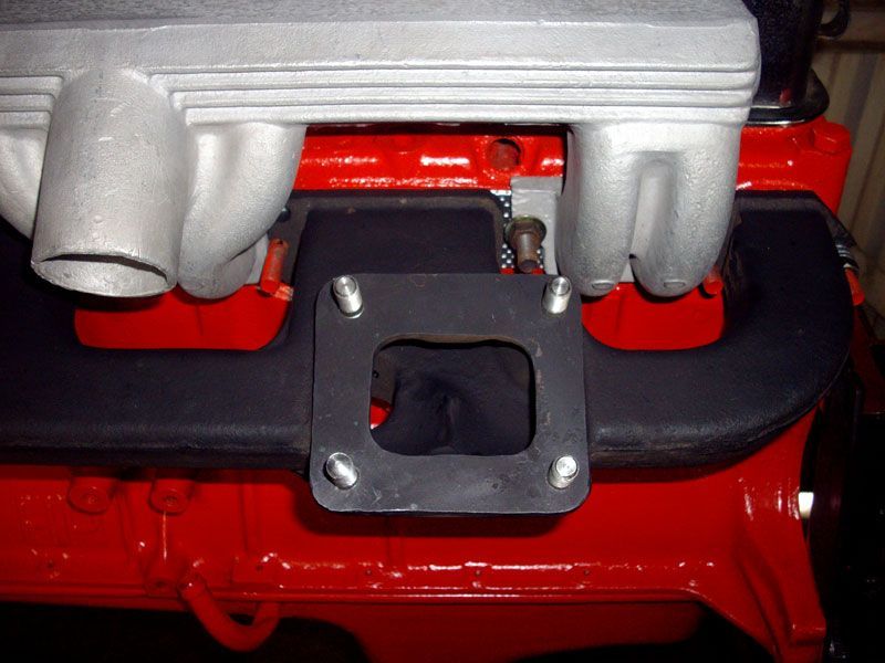 A close up of a red engine with a black intake manifold