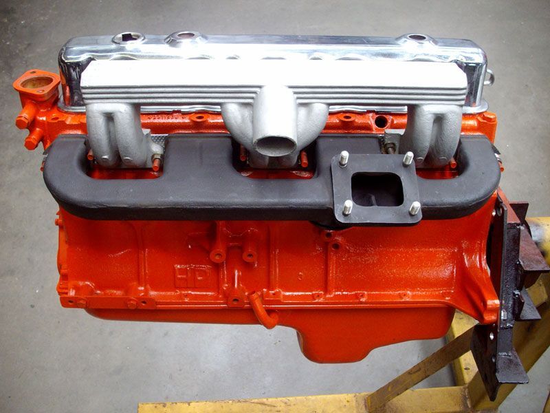 An orange engine sits on a wooden table