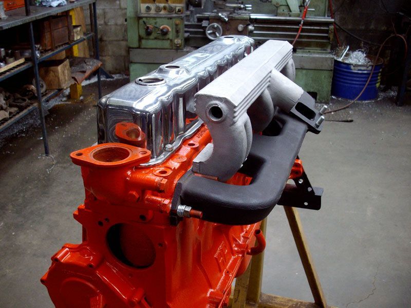 An orange engine is sitting on a wooden stand