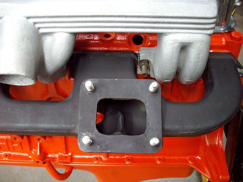 A close up of an orange engine with a black intake manifold