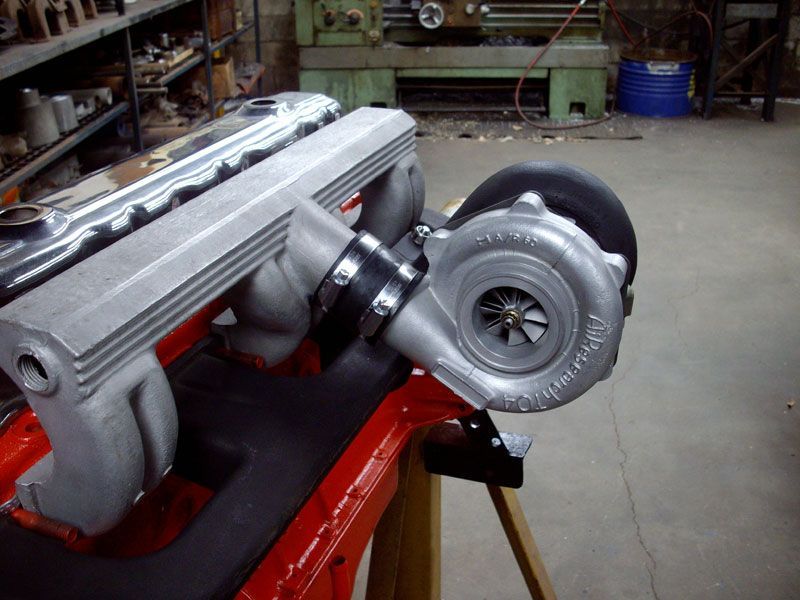 A turbocharger is sitting on top of a red engine