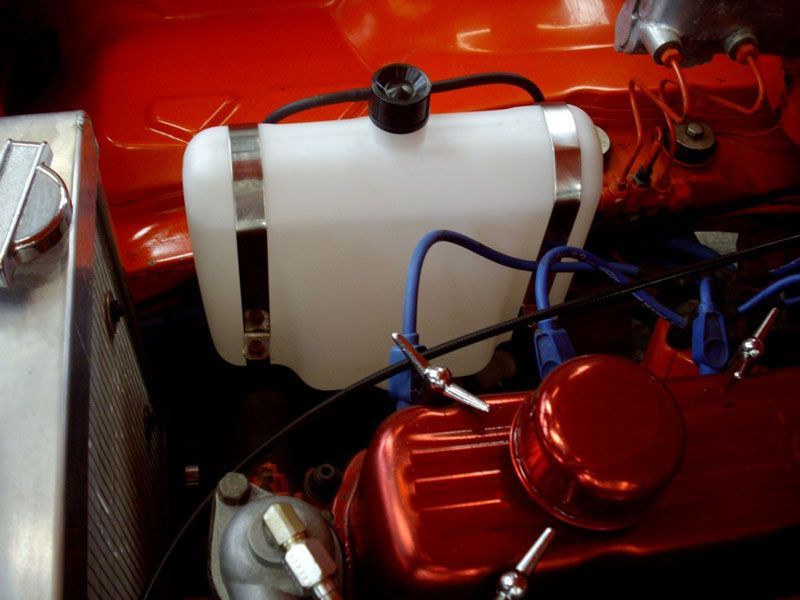 A close up of a car engine with a water tank