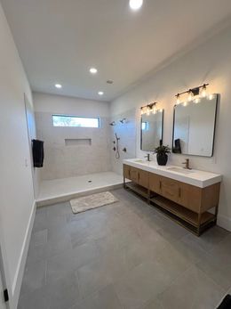 A bathroom with two sinks and a walk in shower.