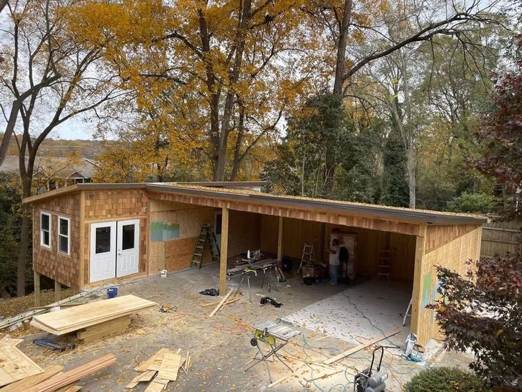 A wooden garage is being built in the backyard of a house.