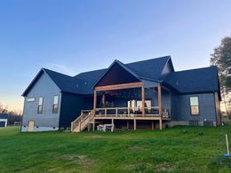 A large house with a screened in porch and a large lawn in front of it.