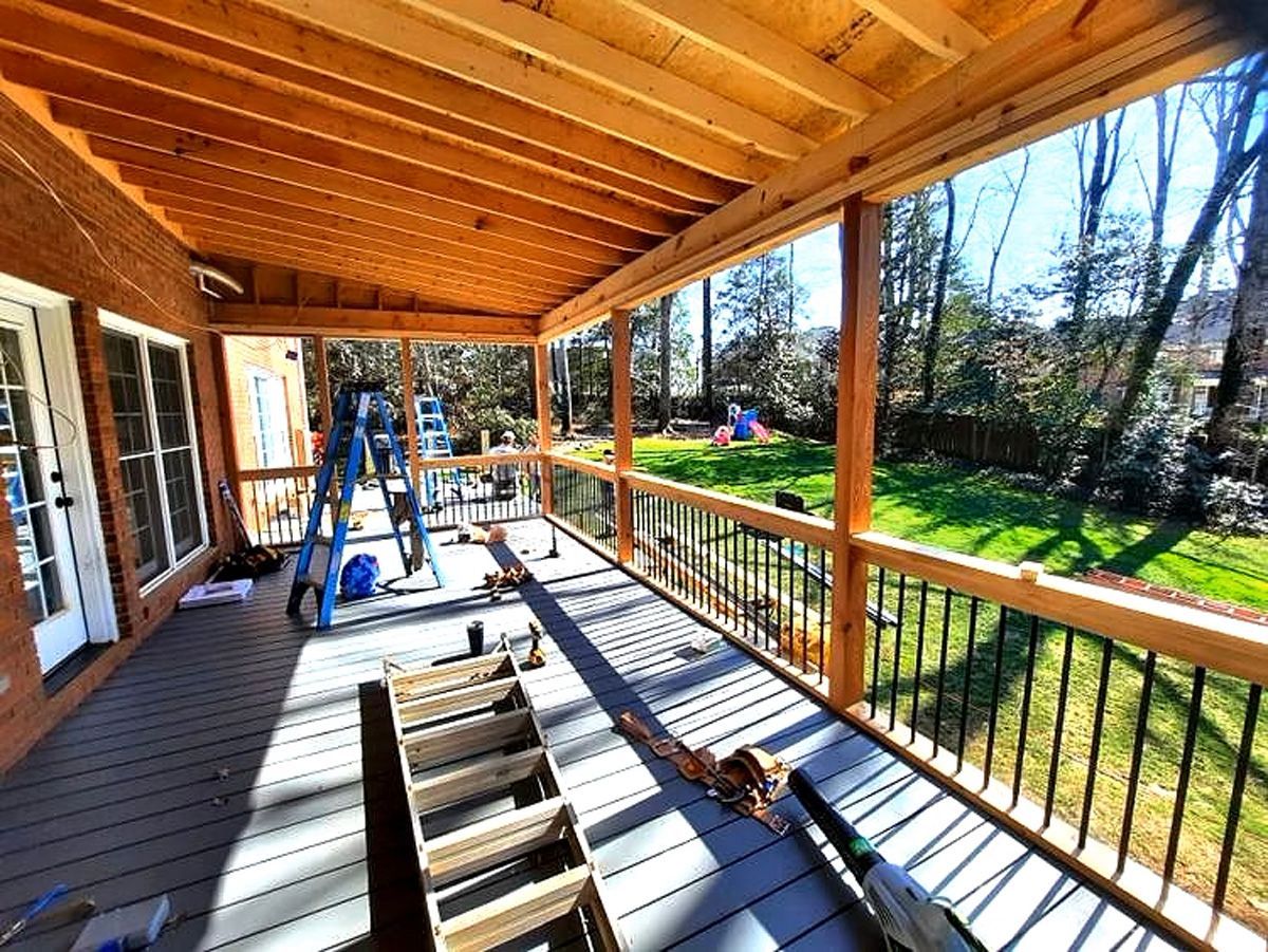 A wooden deck with a metal railing is being built on a sunny day.