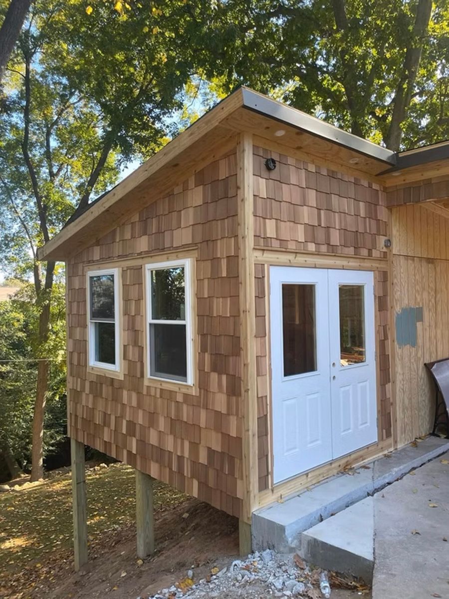 A small wooden house with white doors and windows is sitting on top of a hill.