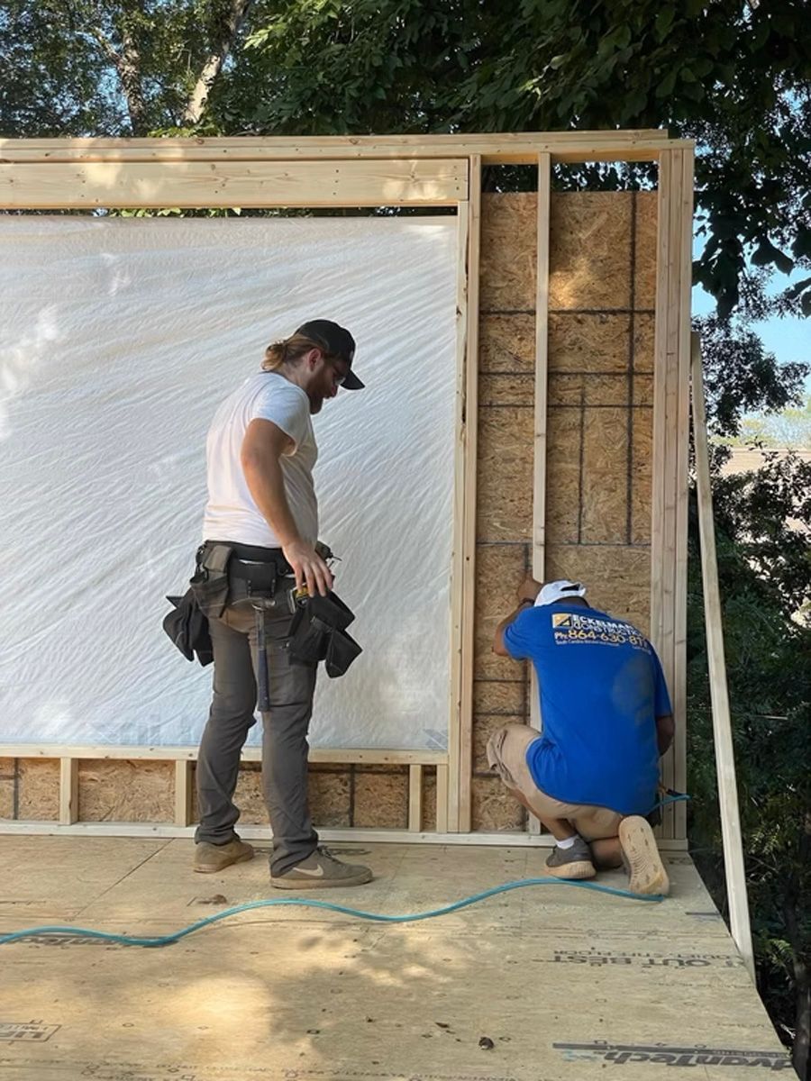 Two men are working on a wall of a house.