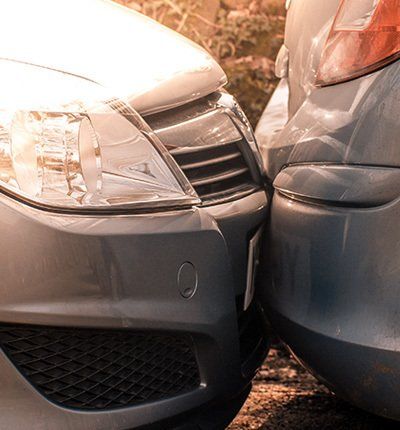 Dos coches, uno gris y otro plateado, se ven involucrados en una pequeña colisión con parachoques tocándose.