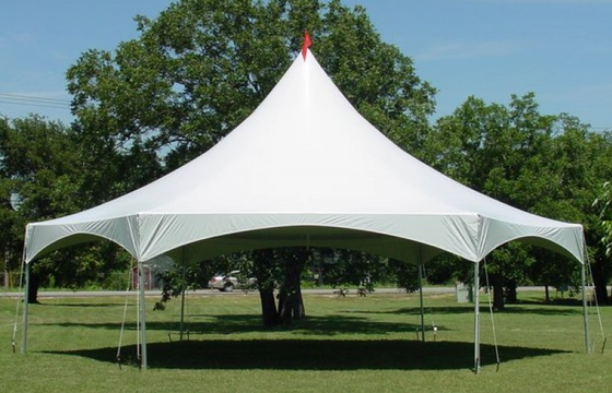 A large white party tent with red stripes on a lawn