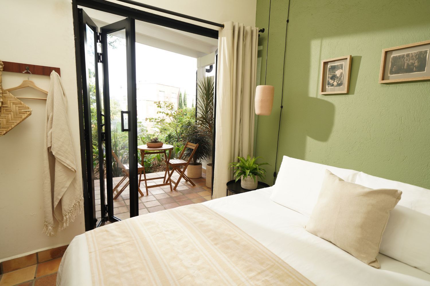 A bedroom with a bed and a balcony with a table and chairs