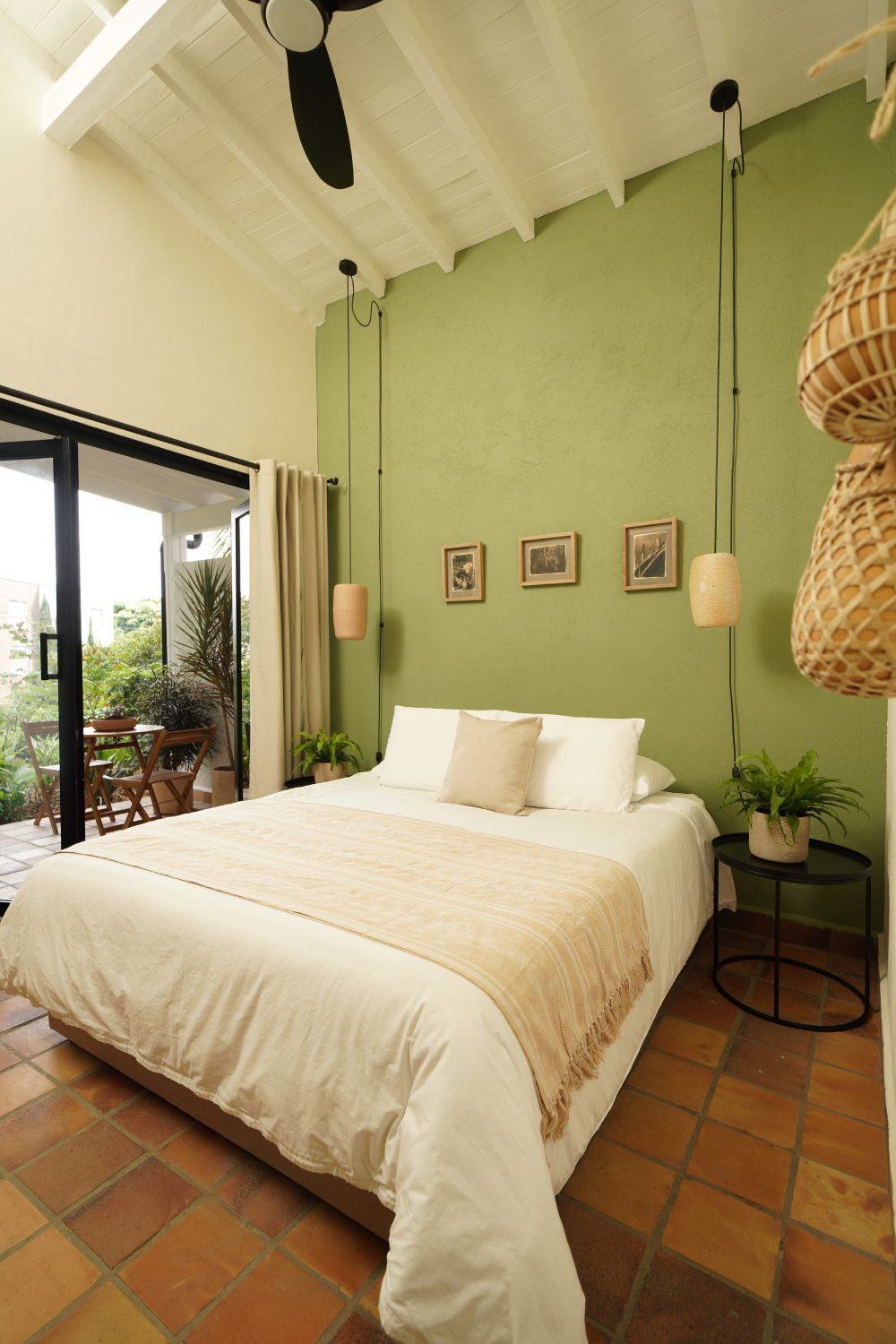 A bedroom with a king size bed , green walls and a ceiling fan.