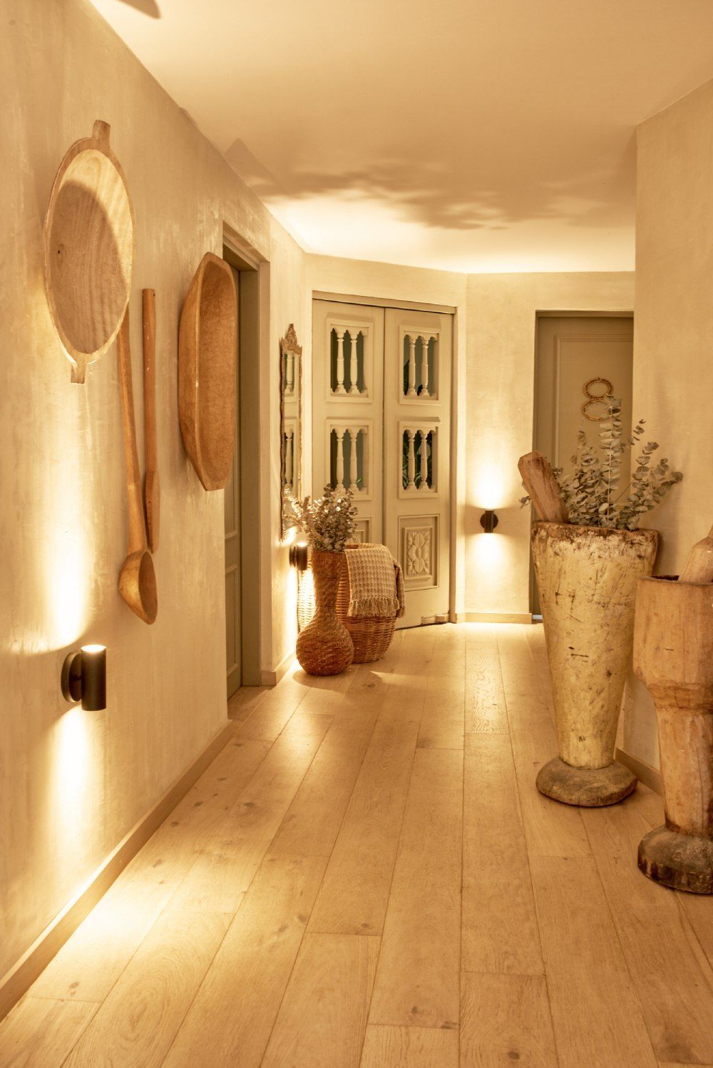 A hallway with wooden floors and a vase on the floor.